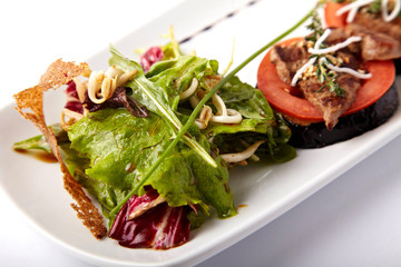 Beef medallions on tomato and grilled eggplant on a white plate