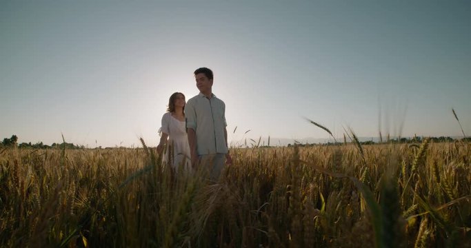 Young loving carefree couple wheat field outdoors sunset silhouette happy healthy lifestyle recreation leisure enjoying togetherness,slow motion