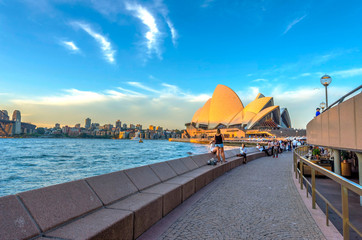 Toeristen lopen naast de operabar voor het Sydney Opera House