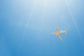 Naklejka premium Samolot pasażerski lecący na błękitne niebo ze światłem słonecznym