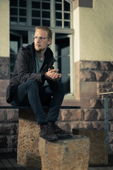 Handsome Young Man Sitting on Stone Furniture