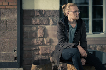 Handsome Young Man Sitting on Stone Furniture