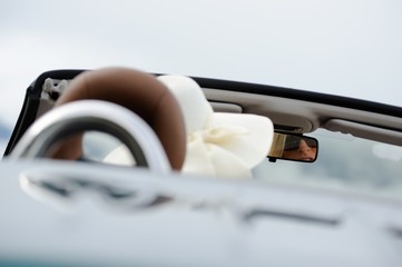 Junge Frau mit Sonnenbrille und Hut sitzt in einem Cabriolet