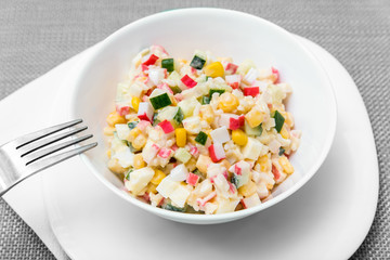Crab salad in a plate on a blue tablecloth, top view