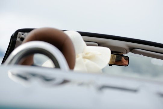 Junge Frau mit Sonnenbrille und Hut sitzt in einem Cabriolet