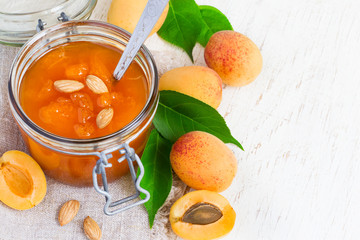 Fresh Apricot jam in jar and fresh fruits with leaves. Top view