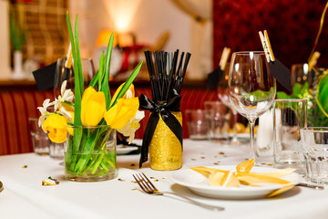Birthday guests table setting with fresh flowers in black and gold style, indoor