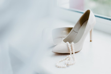 Ivory female wedding footwear with pearls juweliry on the window