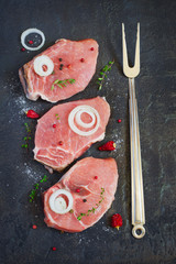 Raw fresh meat, spices and fork on dark background