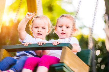 Fototapeta na wymiar Two beautiful little girls swinging in the park.