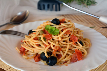 Delicious italian food spaghetti a la puttanesca on a bowl on a table.