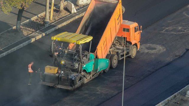Workers operating asphalt paver machines during road construction and repairing works timelapse
