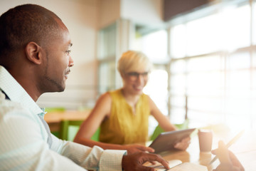 Fototapeta premium Two creative millenial small business owners working on social media strategy using a digital tablet while sitting at desk