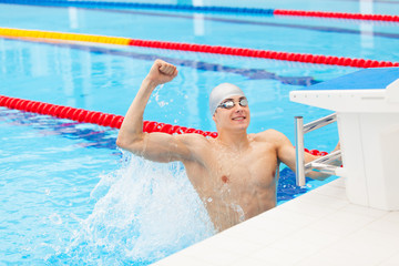Young male swimmer celebrating victory in the swimming pool