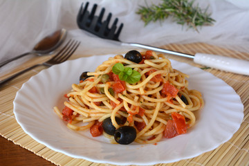 Delicious italian food spaghetti a la puttanesca on a bowl on a table.