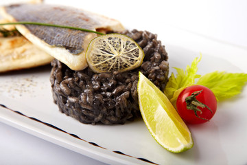 Grilled fish with black risotto on a white background
