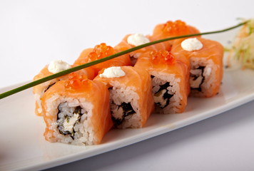 Plate of salmon sushi with lime and ginger on a white background