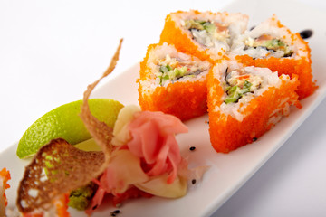 Plate of salmon sushi with lime and ginger on a white background