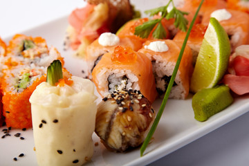 Plate of salmon sushi with lime and ginger on a white background