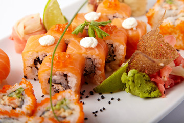Plate of salmon sushi with lime and ginger on a white background