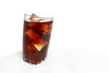 Glass of cola with ice cubes on snow on white