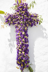 Cruz con flores moradas colgada en una pared blanca en la festividad de las cruces de mayo en...