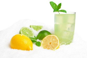 Glass of lime juice,lemons,ice cubes on snow on white