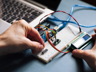 Microchip manual connecting to microcontroller. Top view on engeneer hands working with...
