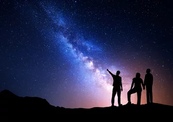 Tuinposter Kleurrijke Melkweg met silhouet van een staande man wijzende vinger in de nachtelijke sterrenhemel en zijn ouders. Silhouet van een familie. Nacht landschap. Prachtig universum, ruimte achtergrond © den-belitsky