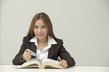Portrait of happy student or bussiness women sitting in library before textbook and looking at camera