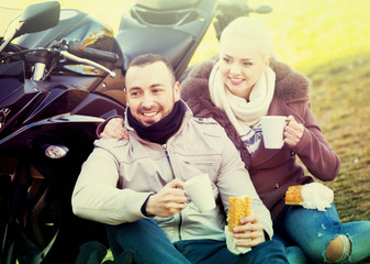 Positive  couple having picnic with coffee