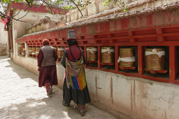 Two women dress in Pilgrims suit rotating praying wheels in Leh