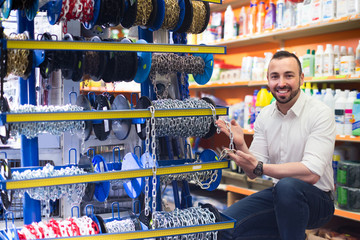 Man selecting metallic chain in household store .