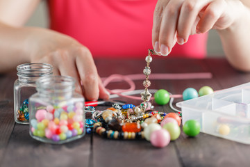 Womanâ€™s hands making bracelete with plastic beads