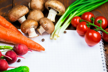 Beautiful background healthy organic eating. Studio photography the frame of different vegetables and mushrooms with a white sheet of paper on the old brown boards with free space