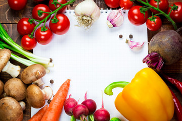 Beautiful background healthy organic eating. Studio photography the frame of different vegetables and mushrooms with a white sheet of paper on the old brown boards with free space