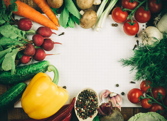 Beautiful background healthy organic eating. Studio photography the frame of different vegetables and mushrooms with a white sheet of paper on the old brown boards with free space