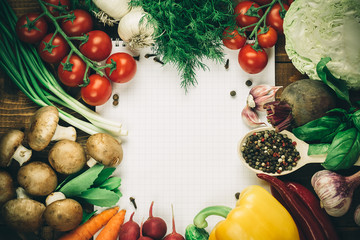 Beautiful background healthy organic eating. Studio photography the frame of different vegetables and mushrooms with a white sheet of paper on the old brown boards with free space