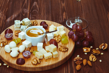 Cheese Board served with grapes and nuts on a wooden background