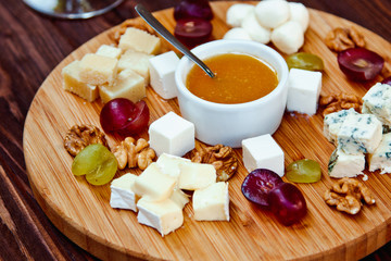 Cheese Board served with grapes and nuts on a wooden background