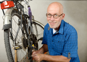 man repairing bicycle in his workshop.