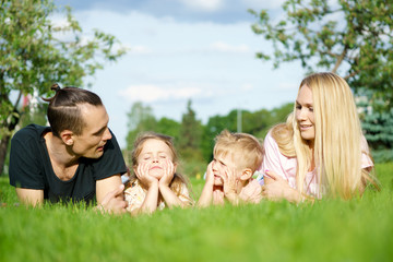 Fototapeta premium Portrait of happy parents with kids lying at the park