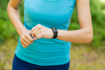 Closeup shot of young female runner arms with sports smartwatch.