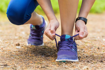 Close up of woman tying shoe laces in summer workout.