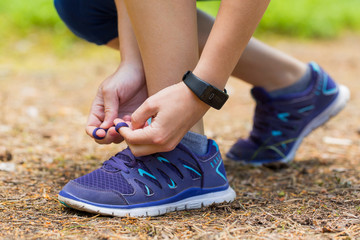Close up of woman tying shoe laces in summer workout.