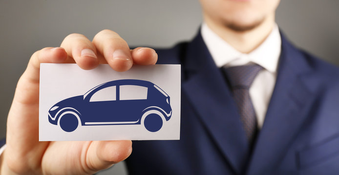 Businessman holding business card with picture of car