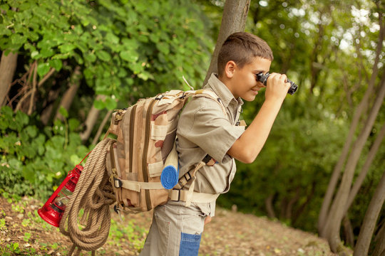 young boy explores  nature with binoculars on camping trip