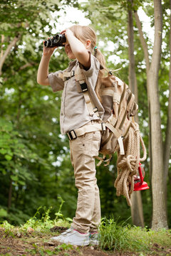 young girl explores  nature with binoculars on camping trip