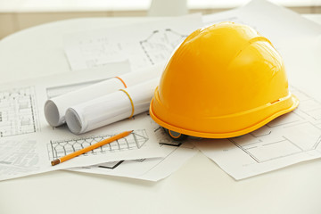 Yellow helmet on the table with blueprints