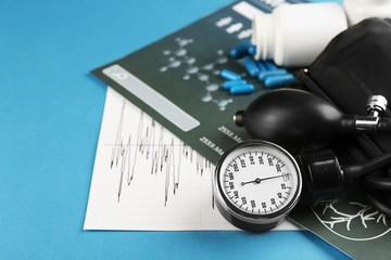 Medical manometer, pills and medical record on blue background